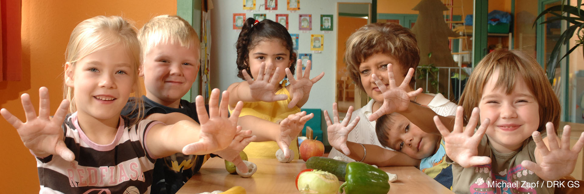 Fröhliche Kita-Kinder halten ihre Hände in die Kamera