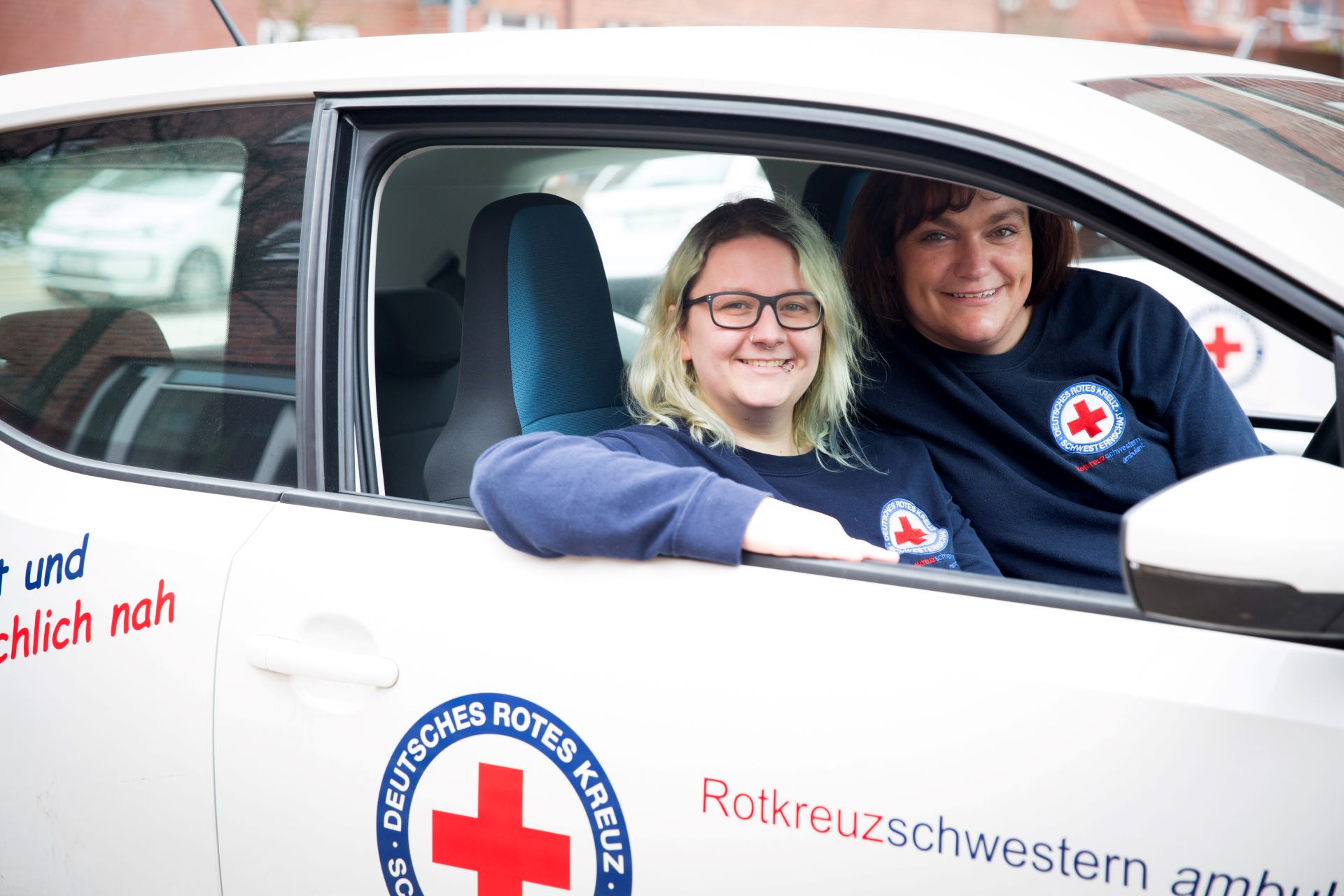 Zwei ambulante Pflegefachkräfte der DRK Schwesternschaft Lübeck sitzen im Firmenauto